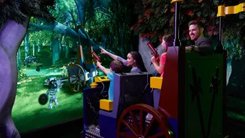 Family on LEGOLAND Discovery Center ride trying to hit targets with blunderbuss
